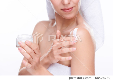 Young woman with small jar of smoothing body cream applying it on shoulder Young woman with small jar of smoothing body cream applying it on shoulder 68528789