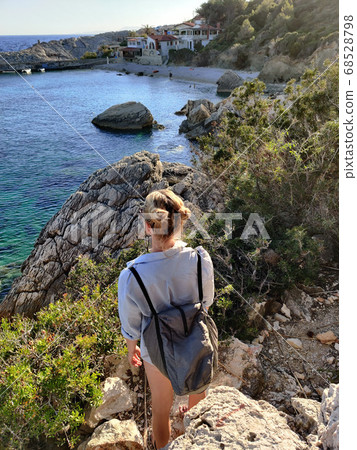 Young active feamle tourist wearing small backpack walking on coastal path among pine trees enjoing beautiful costal view of Velo Zarace beach on Hvar island, Croatia. Travel and adventure concept Young active feamle tourist wearing small backpack walking on coastal path among pine trees enjoing beautiful costal view of Velo Zarace beach on Hvar island, Croatia. Travel and adventure concept 68528798