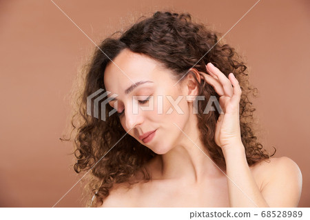Young serene woman touching her luxurious long brown wavy hair 68528989