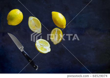 Lemons cuting with fruit Knife in the air on dark background. Food Levitation 68529074