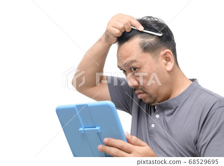 Middle-aged asian man worry about his  hair loss 68529695