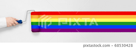 Hand holds a paint roller and paints rainbow 68530428