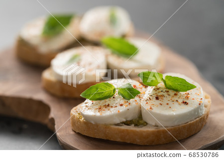Bruschetta with mozzarella, basil and pesto on olive wood board 68530786