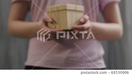 young woman stand and show brown gift box with twine bow young woman stand and show brown gift box with twine bow 68530906