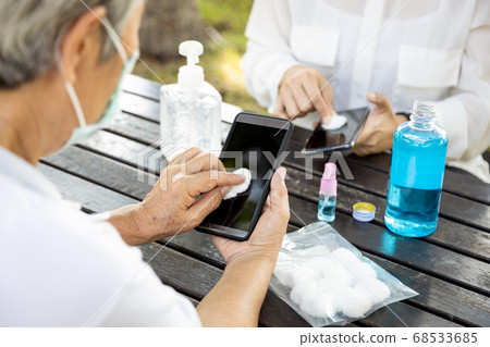 Cleaning mobile phone to prevent Covid-19 infection,asian woman cleaning the phone by hand sanitizer gel,senior people using alcohol to wipe to avoid contamination,disinfection,outbreak of Coronavirus Cleaning mobile phone to prevent Covid-19 infection,asian woman cleaning the phone by hand sanitizer gel,senior people using alcohol to wipe to avoid contamination,disinfection,outbreak of Coronavirus 68533685