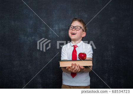 Adorable child whit books and apple in hands. Back to school. Education. Blackboard on background. Kid pupil boy in uniform. Happy child Adorable child whit books and apple in hands. Back to school. Education. Blackboard on background. Kid pupil boy in uniform. Happy child 68534723