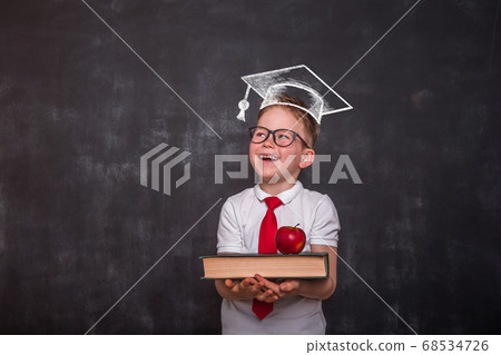 Smart educated school kid student with graduation hat doodle picture on chalkboard. little boy with paintbrush creative drawing light bulb ideas on wall. 68534726