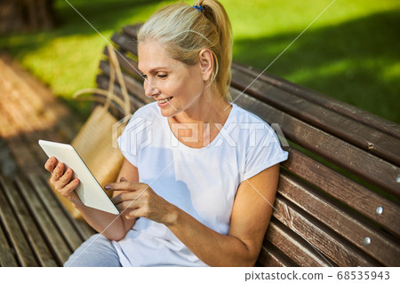 Beautiful joyful woman using tablet computer on the street 68535943