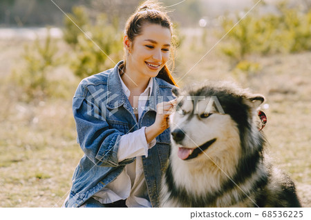 Stylish girl in a spring field with a dog Stylish girl in a spring field with a dog 68536225