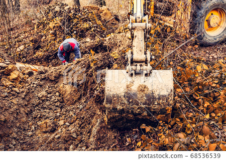 An excavator in the forest digs a ladle for fish An excavator in the forest digs a ladle for fish 68536539