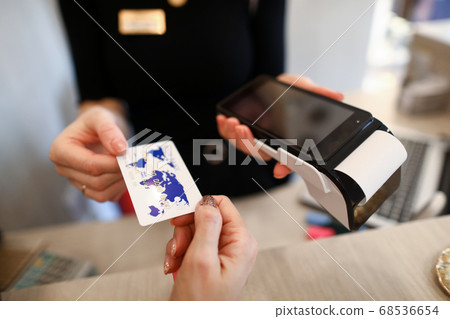 Client holds out credit card for payment terminal Client holds out credit card for payment terminal 68536654