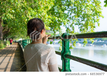 A Japanese woman in her 50s rehydrating on the Thames Riverside while traveling abroad 68536977
