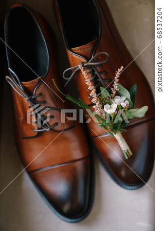 White-colored shoes for the groom on stylish men's brown shoes. White-colored shoes for the groom on stylish men's brown shoes. 68537204