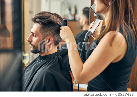 Young hairdresser talking to her handsome client Young hairdresser talking to her handsome client 68537458