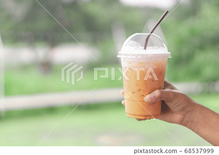 Closeup woman hand holding thai milk tea on wood 68537999