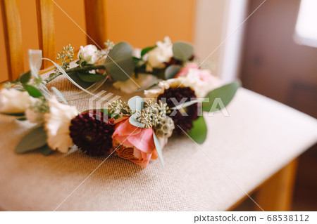 brides wreath of white and pink roses, branches of eucalypt tree and burgundy chrysanthemum with thin ribbons on a textile beige chair brides wreath of white and pink roses, branches of eucalypt tree and burgundy chrysanthemum with thin ribbons on a textile beige chair 68538112
