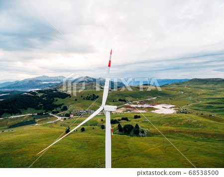 Aerial photo from the drone - a huge wind generator against the background of green meadows and hills in the mountains of Montenegro. Aerial photo from the drone - a huge wind generator against the background of green meadows and hills in the mountains of Montenegro. 68538500