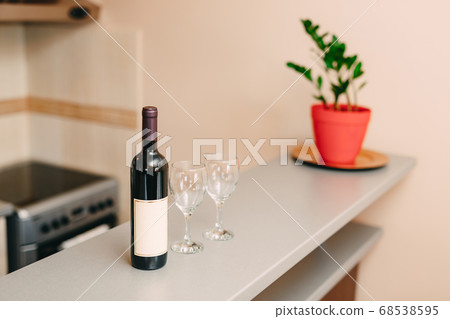 A bottle of wine and two empty glasses on the bar in the kitchen. A bottle of wine and two empty glasses on the bar in the kitchen. 68538595