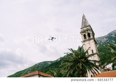 A small drone flies in the sky above the chapel of the church in Perast, Montenegro. 68538777