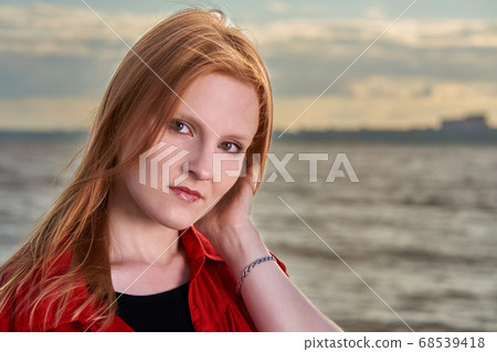 Portrait of a young red-haired girl in a red shirt Portrait of a young red-haired girl in a red shirt 68539418