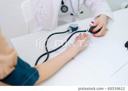 Close-up hands of unrecognizable female doctor measuring young pregnant woman patient pulse pressure Close-up hands of unrecognizable female doctor measuring young pregnant woman patient pulse pressure 68539612