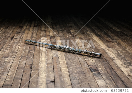 silver metal flute lies on a wooden stage in the 68539751