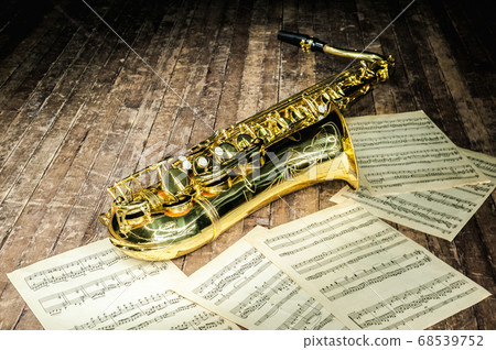 shiny golden saxophone lies near sheet music 68539752