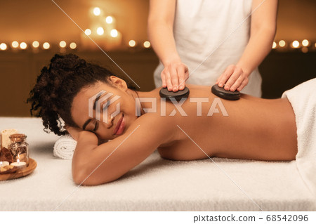 Spa therapist making professional hot stone massage Spa therapist making professional hot stone massage 68542096