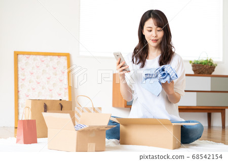 A young woman online shopping to check clothes bought at Mercari A young woman online shopping to check clothes bought at Mercari 68542154