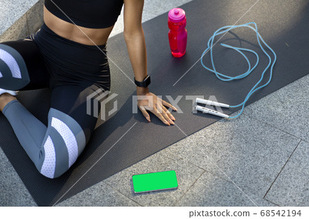 Girl resting on yoga mat, having smartphone with blank screen Girl resting on yoga mat, having smartphone with blank screen 68542194