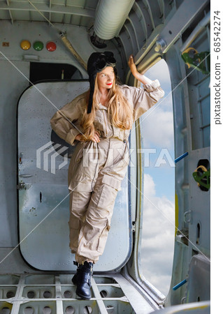 Young woman in a pilot's suit stands at the opened 68542274