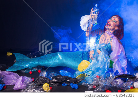 Fantasy stupid mermaid in deep ocean. Plastic water bottles and bags pollution on sea floor. Environmental problem. 68542325