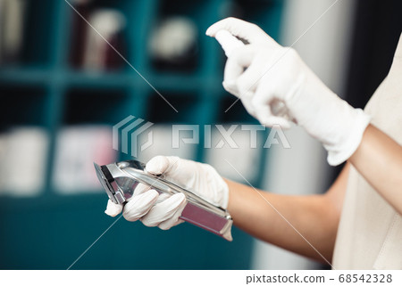 Master disinfecting trimmer after work, close up 68542328