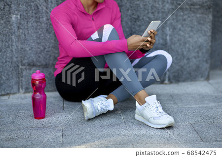 Cropped of black girl in sport clothes using smartphone Cropped of black girl in sport clothes using smartphone 68542475