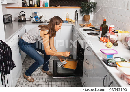 A woman is baking cake in a kitchen oven 68543190