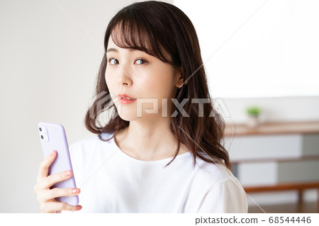 Anxious face young woman operating a smartphone in the living room Anxious face young woman operating a smartphone in the living room 68544446