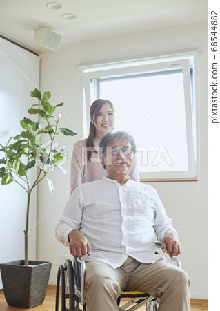Young woman assisting senior man in wheelchair 68544882