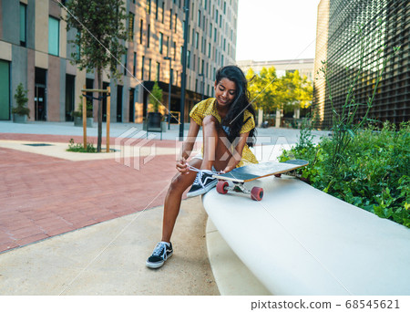pretty athletic girl sitting with a longboard in modern city 68545621