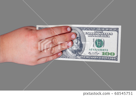 Man's hand holds a banknote of 100 US dollars with 68545751