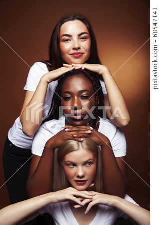 young pretty asian, caucasian, afro woman posing cheerful together on brown background, lifestyle diverse nationality people concept 68547141