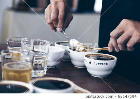 professional Q Grader preparing to test and inspecting coffee quality and skim off coffee grounds. professional Q Grader preparing to test and inspecting coffee quality and skim off coffee grounds. 68547594