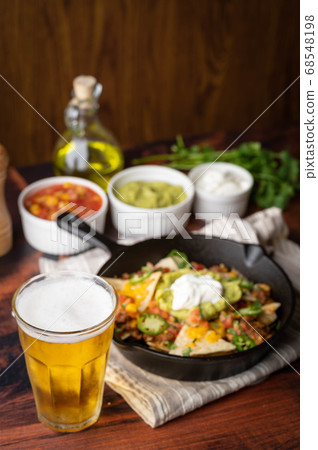 nacho in skillet pan with a glass of beer 68548198