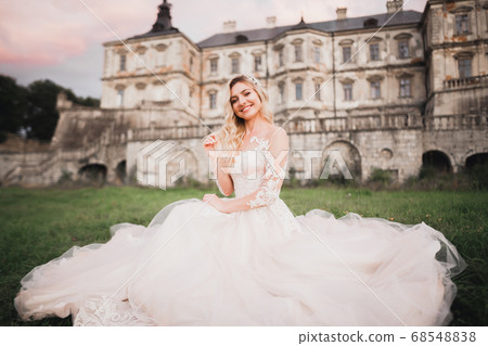 Beautiful bride in elegant white dress holding bouquet posing in park Beautiful bride in elegant white dress holding bouquet posing in park 68548838