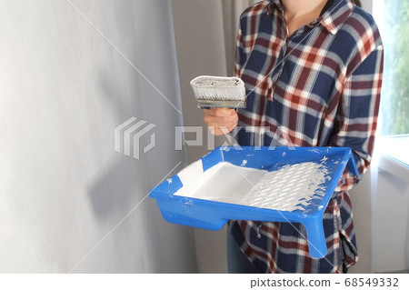 Woman house painter painting wall using brush doing renovation, hand closeup. 68549332