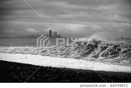 Splashing storm with big waves hitting the sea coast in the evening. Black and white photo 68549652