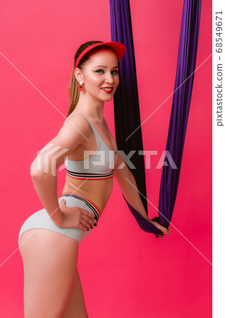 Portrait sexy attractive strong sporty young womant trainer in retro swimsuit standing put hand on hip hold onair silk looking at camera with smile isolated over pink red background Portrait sexy attractive strong sporty young womant trainer in retro swimsuit standing put hand on hip hold onair silk looking at camera with smile isolated over pink red background 68549671