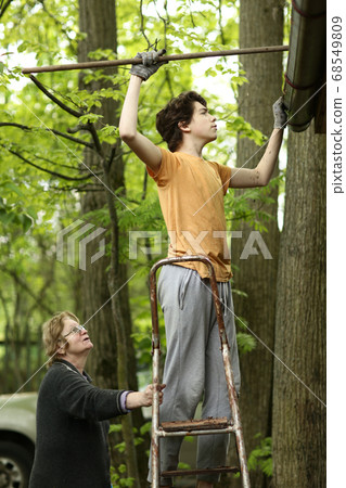 closeup photo of teenager boy and grandma cleaning roof from old leafs closeup photo of teenager boy and grandma cleaning roof from old leafs 68549809