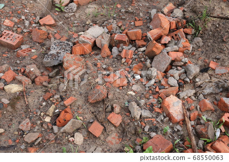 A broken brick lies on the wet ground A broken brick lies on the wet ground 68550063