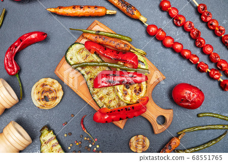 grilled vegetables on a wooden board on a black table, top view 68551765