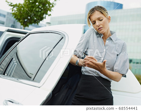 Businesswoman Takes Notes On Palm Of Hand During Phone Call 68554441